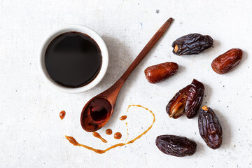 Natural date syrup in a bowl with whole dates in the background - obrazy, fototapety, plakaty