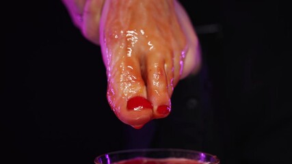 Tomato juice flows down a woman's beautiful red pedicure leg into a glass of ice. Outrageous cocktail serving
