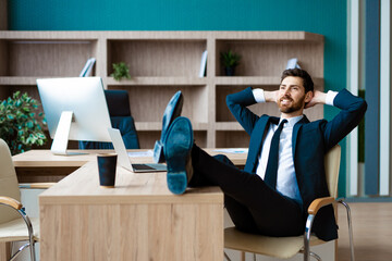 Businessman sitting at computer desk in the office relaxing
