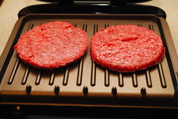 Two Raw Hamburgers on an Indoor Grill