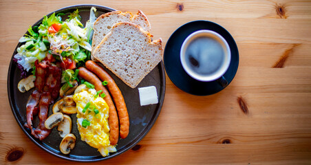 Breakfast with scrambled eggs, bacon, sausages and toast