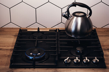 Kettle with a whistle on the gas stove. Built-in gas panel. The kettle is on the stove.
