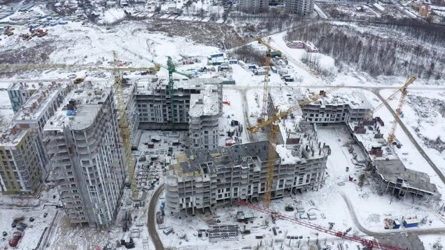 Aerial view of construction site in winter city. Building construction, construction industry. Construction workers on a building site with crane.