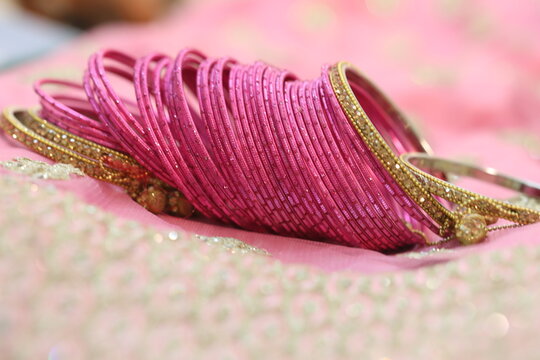 dozens of pink glass decorative bangles spread on pink lehenga