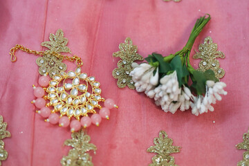 pink kundan stone studded brooch on a pink fabric with a broad designer border