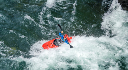 River kayaker in red kayak are paddling whitewatered river. Extreme sports and adrenaline concept....