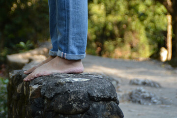 Someone wearing jean stand on the rock at the waterfall.