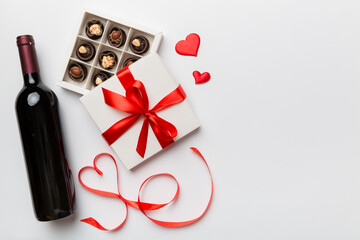 Bottle of red wine on colored background for Valentine Day with gift and chocolate. Heart shaped...
