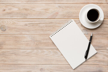 Modern office desk table with notebook and other supplies with cup of coffee. Blank notebook page for you design. Top view, flat lay