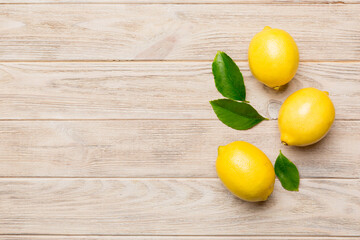 Many fresh ripe lemons with green leaves on colored background, top view, space for text
