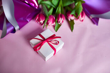 Top view pink tulips flowers in violet paper wrapper with gift box, festive background, concept of Happy Mother's day, Woman's day, birthday, 8 March, Valentines day