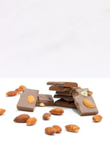 chocolate bars with peanuts, almonds and dried beans on a white background