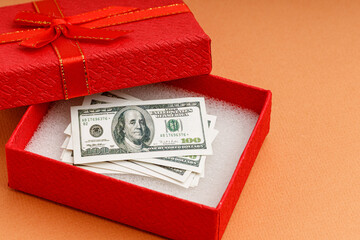 dollars in an open red gift box