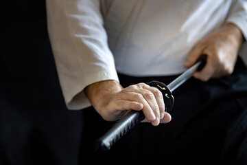 martial arts fighter in a white kimono pulls his sword out of its scabbard