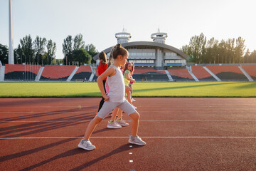 Obraz premium A large group of girls, got ready at the start before running at the stadium during sunset. A healthy lifestyle.