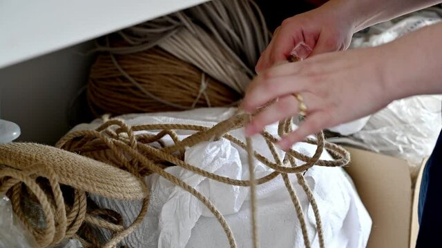 Female hands pulling on a jute rope and undoing knots in the rope to be used in diy projects