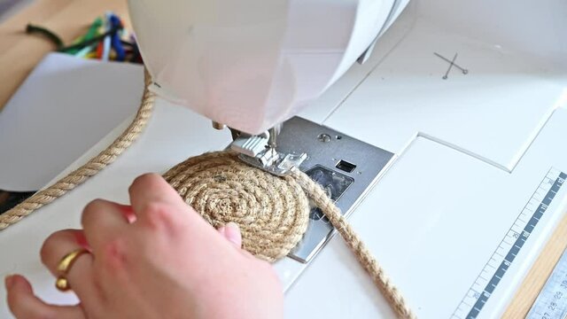 Close up of hand guiding a juste rope in a sewing machine to create a spiral to create a trendy and fashionable home decor accessory