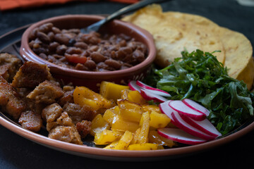 Vegan taco bowl consisting of roasted seitan, bell pepper, salad, refried beans