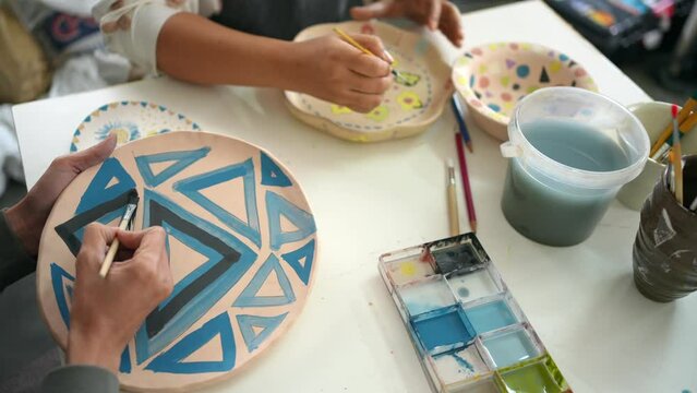 4K Asian woman learning color painting self-made pottery plate with friends at home. Confidence female enjoy leisure activity handicraft hobbies ceramic sculpture painting workshop at pottery studio.
