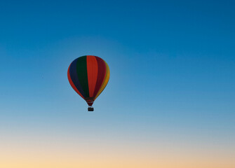 Colorful hot air balloon flying through the sky while the sun is setting