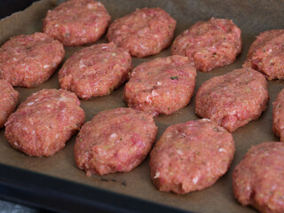 Raw meat cutlets in a backing tray ready to be cooked