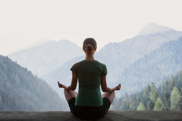 Young woman practicing yoga in mountains at sunset. Harmony, meditation, healthy lifestyle,...