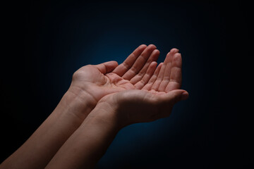 opening palms over dark background, begging gesture