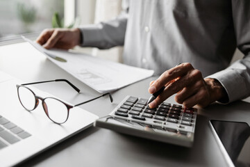 Accountant calculate finance report using calculator and holding document closeup, business man...
