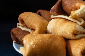 Pancakes with filling in a plate on a black background