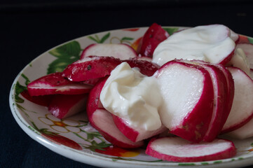 Red radish with sour cream in a plate on the table