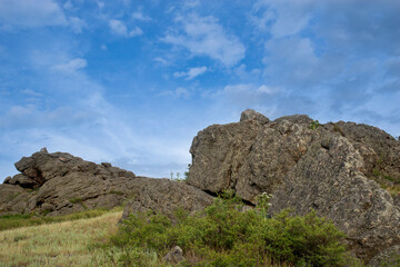 Rocks on a green hill against a blue sky. Close-up. The concept of nature - 482201467