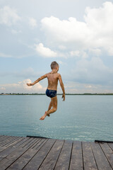 Fototapeta na wymiar Happy smiling boy enjoying summer vacation on the beach. Jumping to the water. Having fun