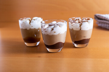 Assortment of mini chocolate and nuts desserts in the glass. Mini choloate desserts on a wood background.