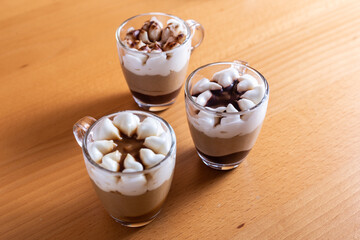 Assortment of mini chocolate and nuts desserts in the glass. Mini choloate desserts on a wood background.