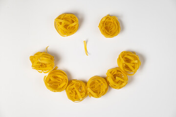 few homemade fettuccine nest in the shape of a smiley face isolated on white background