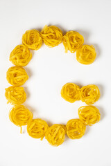 few homemade fettuccine nest in the shape of the letter F isolated on white background