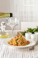 Lifestyle italian dinner. Linguine pasta with salmon and zucchini. White wine. Vertical image.