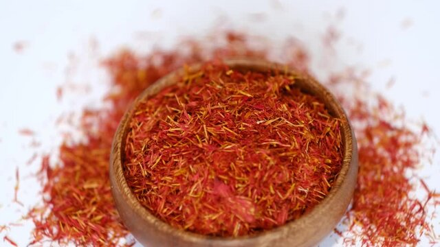 wooden bowl of saffron rotates around itself. saffron thread in the wooden plate, isolated on white background. stock footage. slow motion.