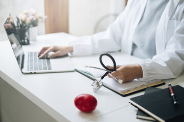 Portrait of doctor smiling wearing eyeglasses and showing stethoscope tools at office in private...
