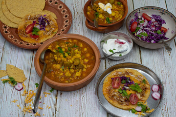 Vegetarian okra pozole and corn quesadillas in traditional Mexican clay dishes, wooden table.