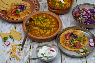 Vegetarian okra pozole and corn quesadillas in traditional Mexican clay dishes, wooden table.