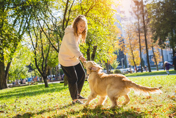 The owner plays the golden retriever dog in the park.