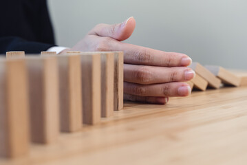 Protection finance from domino effect concept. Hands stop domino effect before destroy stack of money.