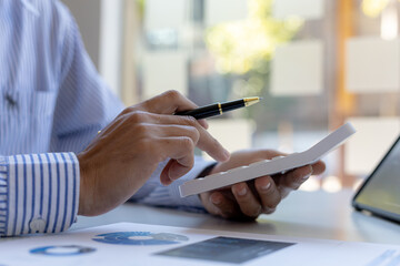 Fototapeta premium Businessman using a calculator to calculate numbers on a company's financial documents, he is analyzing historical financial data to plan how to grow the company. Financial concept.