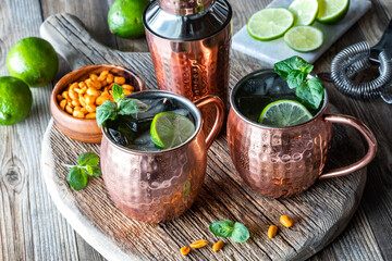 Moscow Mule cocktails garnished with mint and lime and served with peanuts.