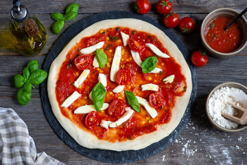 unbaked pizza with tomatoes, mozzarella cheese and basil, preparation