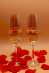 due flûte di spumante su un tavolo pieno di petali di rosa 