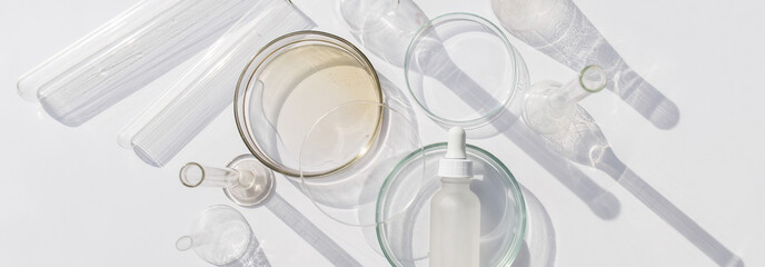 Banner Top view of laboratory glassware and cosmetic glass bottle on grey background. Natural medicine, cosmetic research, bio science, organic skin care products.