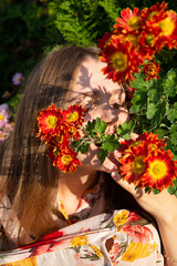 Naklejka premium Portrait of young woman with white skin with greenery behind and flowers in front