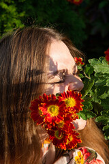 Naklejka premium Portrait of young woman with white skin with greenery behind and flowers in front